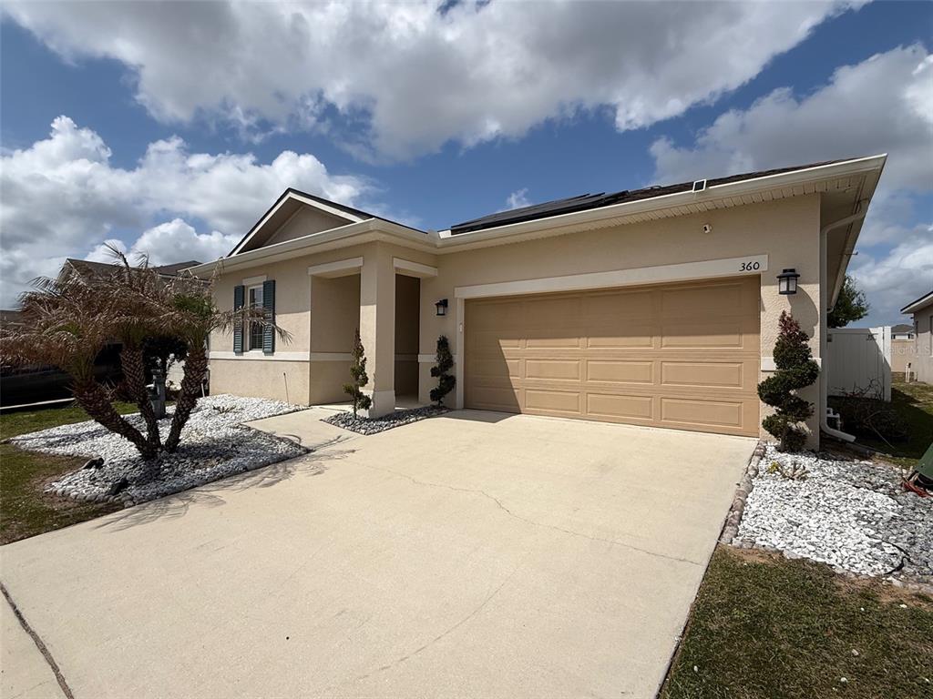 A single-story house with a beige stucco exterior, a two-car garage, and a concrete driveway — 360 BUCHANNAN DRIVE, DAVENPORT, FL