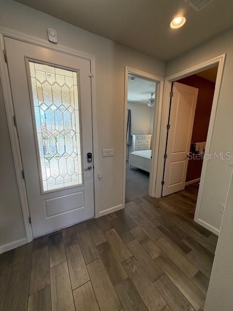 A hallway with wood-look tile flooring leads to a front door and an open bedroom — 360 BUCHANNAN DRIVE, DAVENPORT, FL