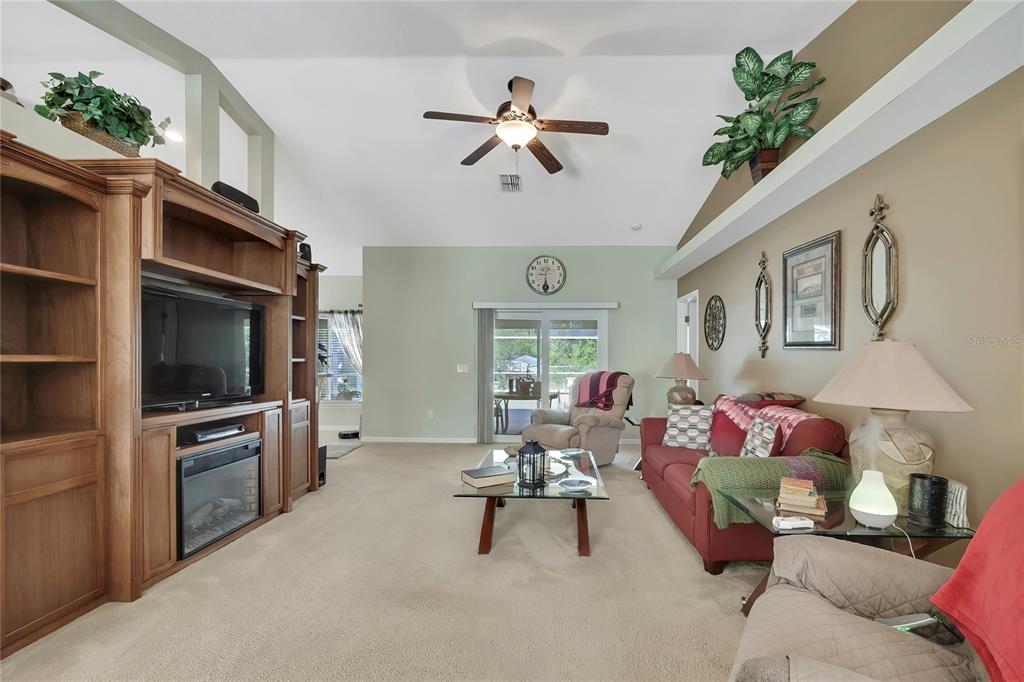 A living room features a wooden entertainment center, a red sofa, and a vaulted ceiling — 15157 DUCK HAWK ROAD, WEEKI WACHEE, FL