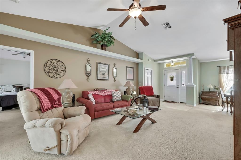 A living room features a vaulted ceiling, beige carpet, a red sofa, and a recliner — 15157 DUCK HAWK ROAD, WEEKI WACHEE, FL