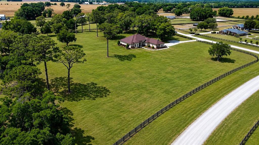 An aerial view shows a house situated on a large, fenced grassy lot with trees — 1145 NW 63RD COURT, OCALA, FL