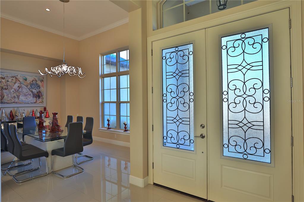 A dining room with a glass table and chairs sits beside a double front door — 1145 NW 63RD COURT, OCALA, FL