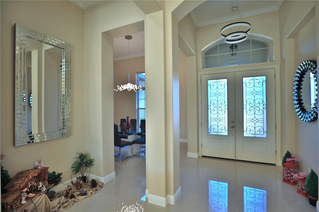 A bright foyer features tile flooring, double glass-paneled entry doors, and a view into a dining room — 1145 NW 63RD COURT, OCALA, FL