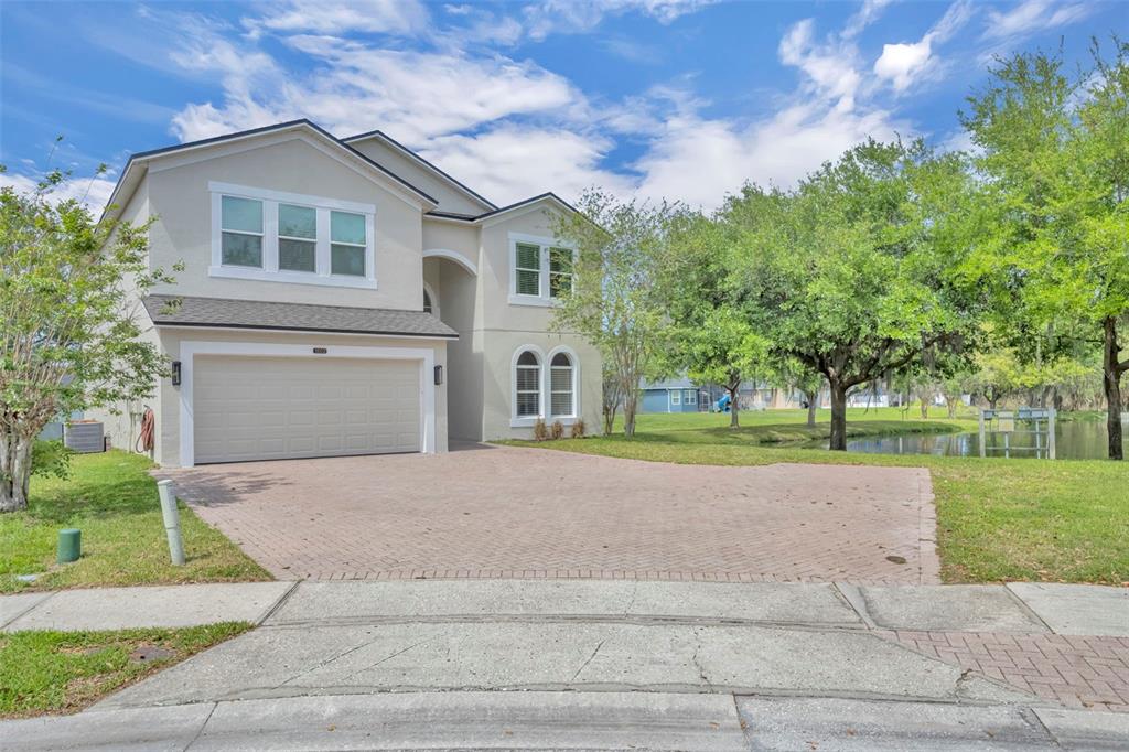 A two-story house with a beige stucco exterior, a two-car garage, and a brick driveway — 1502 ASHDOWN COURT, SANFORD, FL