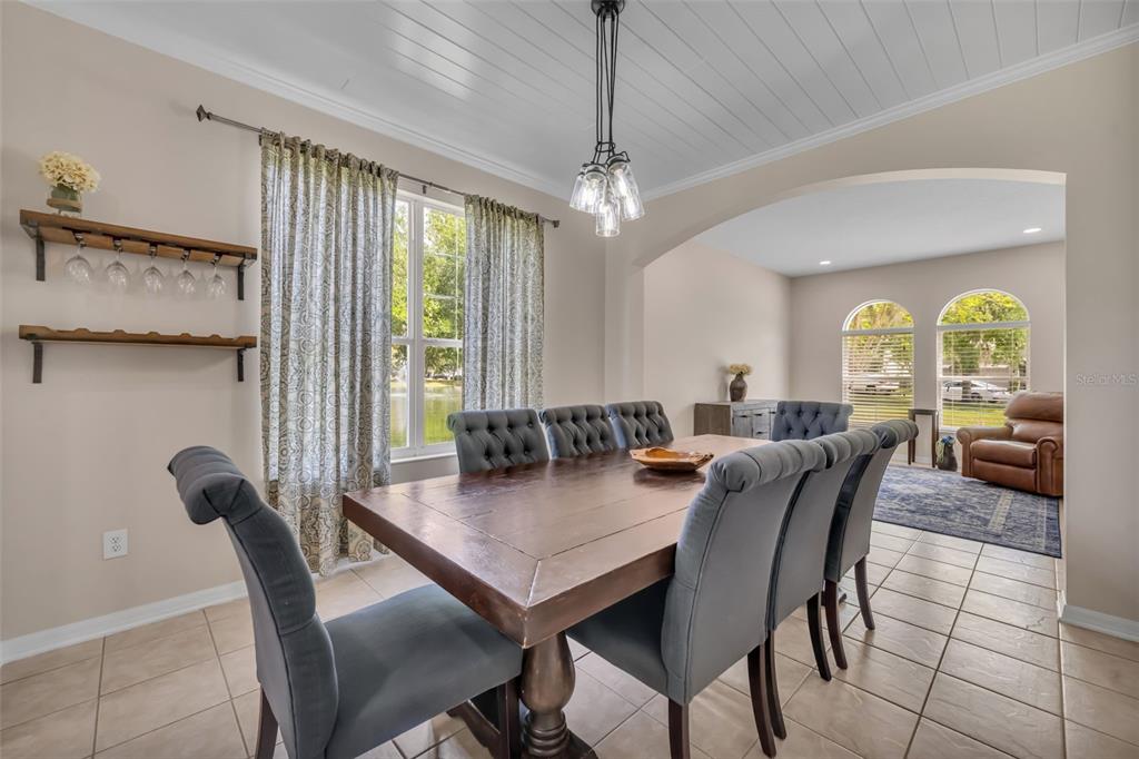 A dining room features a wooden table, gray tufted chairs, and a planked ceiling — 1502 ASHDOWN COURT, SANFORD, FL