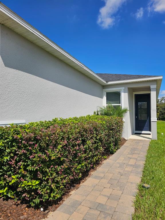 A paved walkway leads to a dark blue door on the side of a house — 2927 SANCTUARY DRIVE, CLERMONT, FL