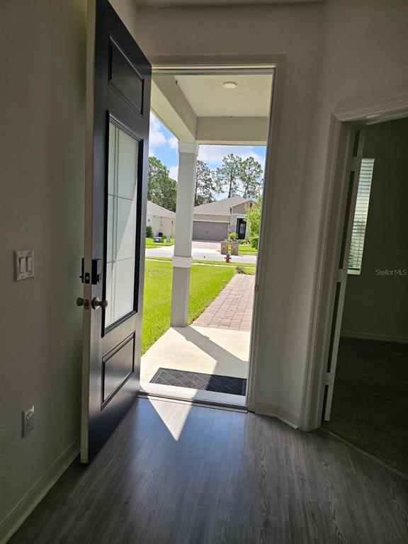 An open front door reveals a view of a suburban street and a neighboring house — 2927 SANCTUARY DRIVE, CLERMONT, FL