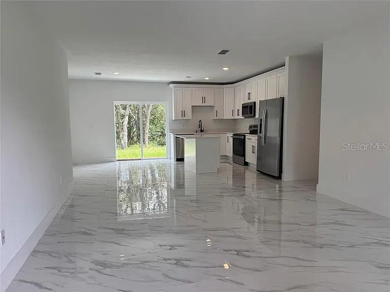 A kitchen with white cabinets, stainless steel appliances, and polished marble-look tile flooring — 2007 W HAMPSHIRE BOULEVARD, CITRUS SPRINGS, FL