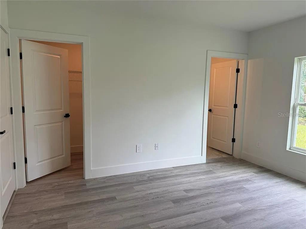 A bedroom with light gray wood-look flooring, white walls, and two open doorways — 2007 W HAMPSHIRE BOULEVARD, CITRUS SPRINGS, FL