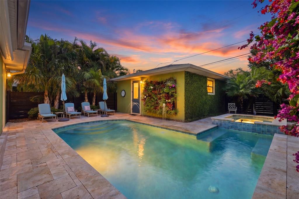 A backyard swimming pool and hot tub sit beside a small building with a living wall — 2344 2ND AVENUE N, ST PETERSBURG, FL