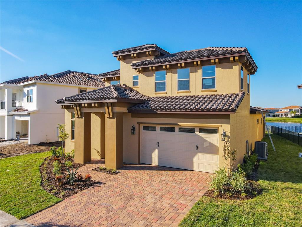 A two-story stucco house with a tile roof, brick paver driveway, and attached garage — 13899 LARKTON LANE, ORLANDO, FL