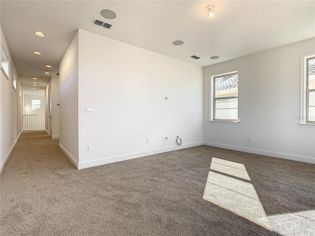 An empty carpeted room features white walls, recessed lighting, and a window — 13899 LARKTON LANE, ORLANDO, FL