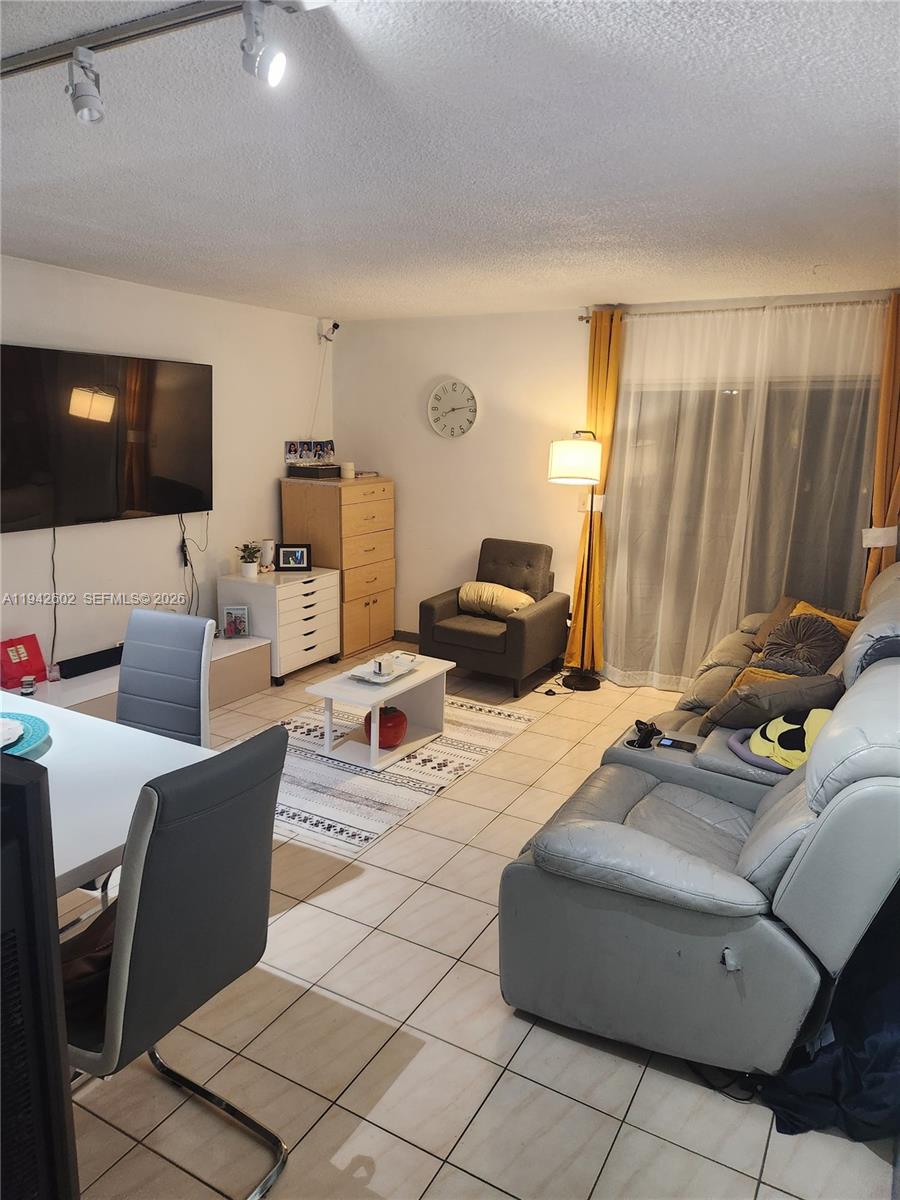 A living room features tile flooring, a gray sofa, a coffee table, and a wall-mounted television — 2498 SW 17th Ave # 4209, Miami FL 33145, MIAMI, FL