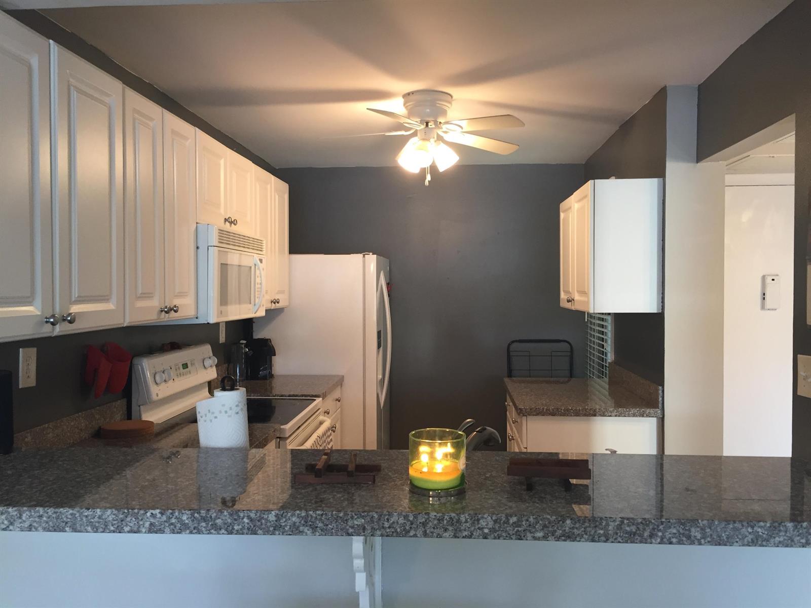 A kitchen features white cabinets, granite countertops, a ceiling fan, and dark gray walls — 10 Royal Palm Way # 2030, Boca Raton FL 33432, BOCA RATON, FL
