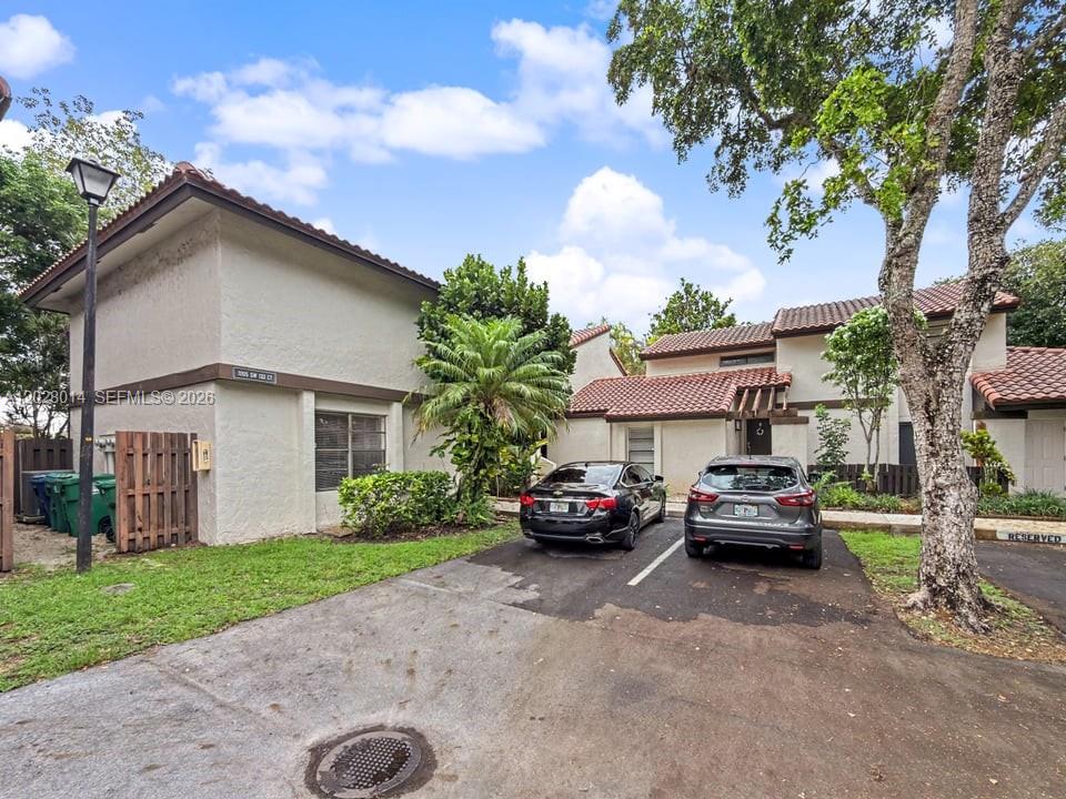 A two-story stucco townhouse with a tile roof, two parked cars, and a paved driveway — 11105 SW 132nd Ct # 4, Miami FL 33186, MIAMI, FL
