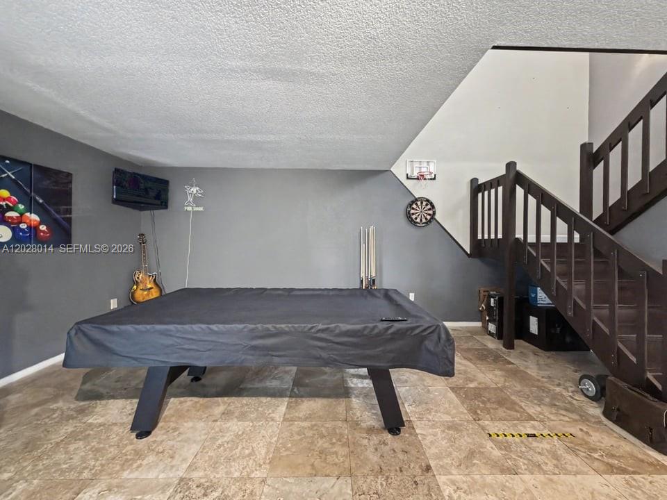 A game room features a covered pool table, a dartboard, and a wooden staircase — 11105 SW 132nd Ct # 4, Miami FL 33186, MIAMI, FL