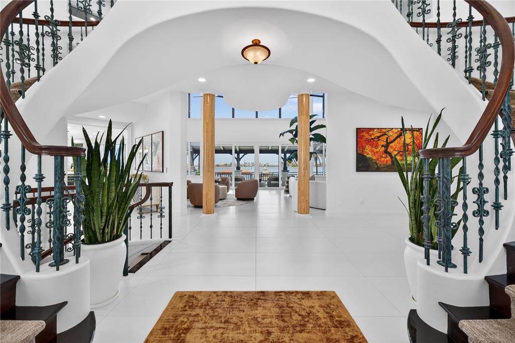 A grand foyer features white tile floors, dual staircases, and a view of the water — 12925 42ND TERRACE W, CORTEZ, FL