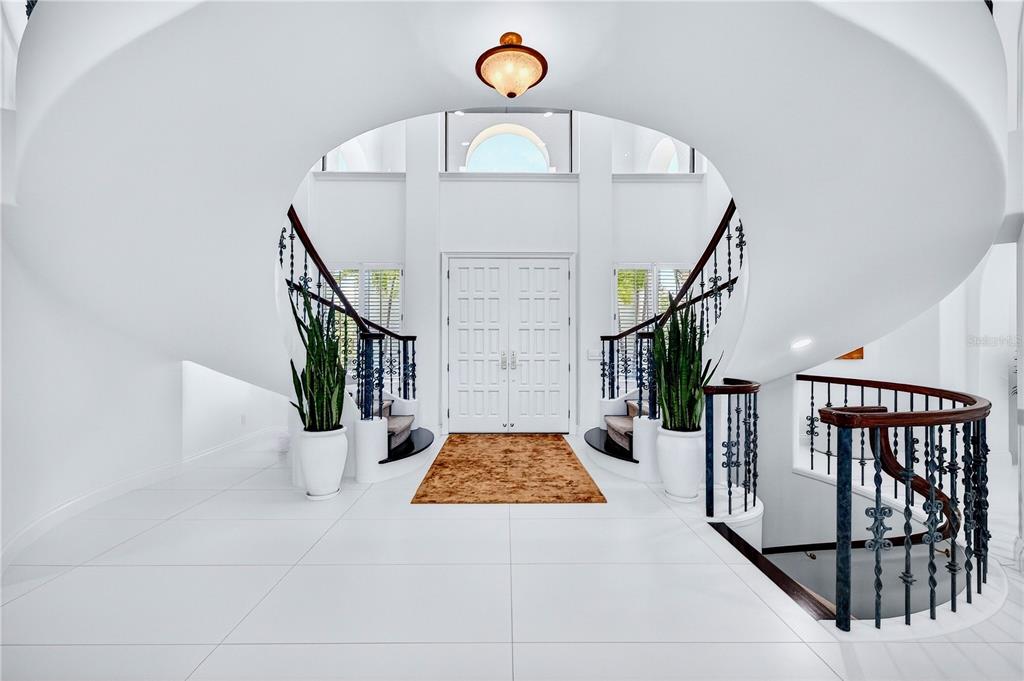 A grand foyer features white tile floors, a double staircase, and a central front door — 12925 42ND TERRACE W, CORTEZ, FL