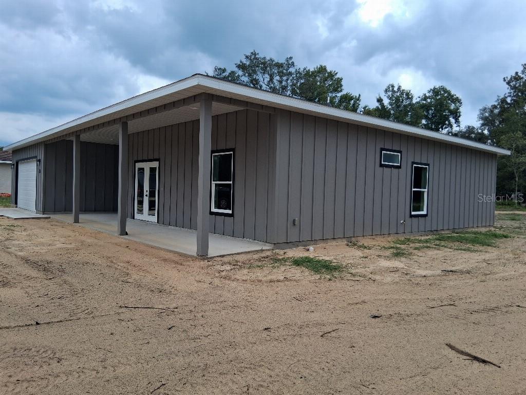 A gray board-and-batten house exterior features a covered porch and a side-entry garage — 9469 SE 154TH STREET, SUMMERFIELD, FL