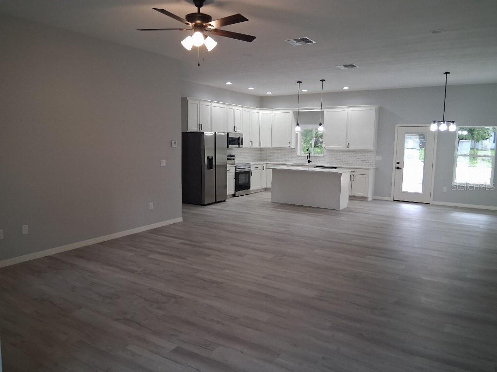 An open-concept kitchen features white cabinets, stainless steel appliances, and a central island — 9469 SE 154TH STREET, SUMMERFIELD, FL