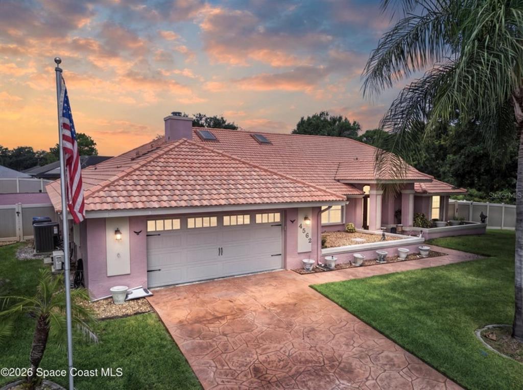A pink single-story house with a tiled roof, a two-car garage, and a flag pole — 4562 HELENA DRIVE, TITUSVILLE, FL