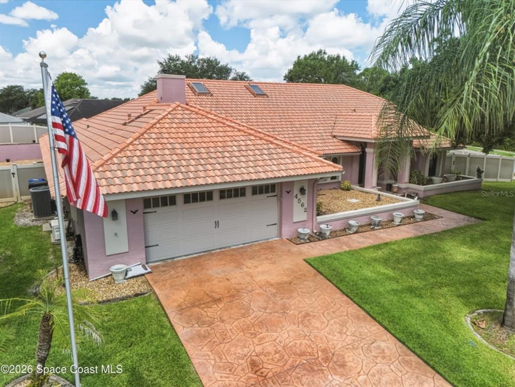 An exterior view of a pink house with a tiled roof and a paved driveway — 4562 HELENA DRIVE, TITUSVILLE, FL