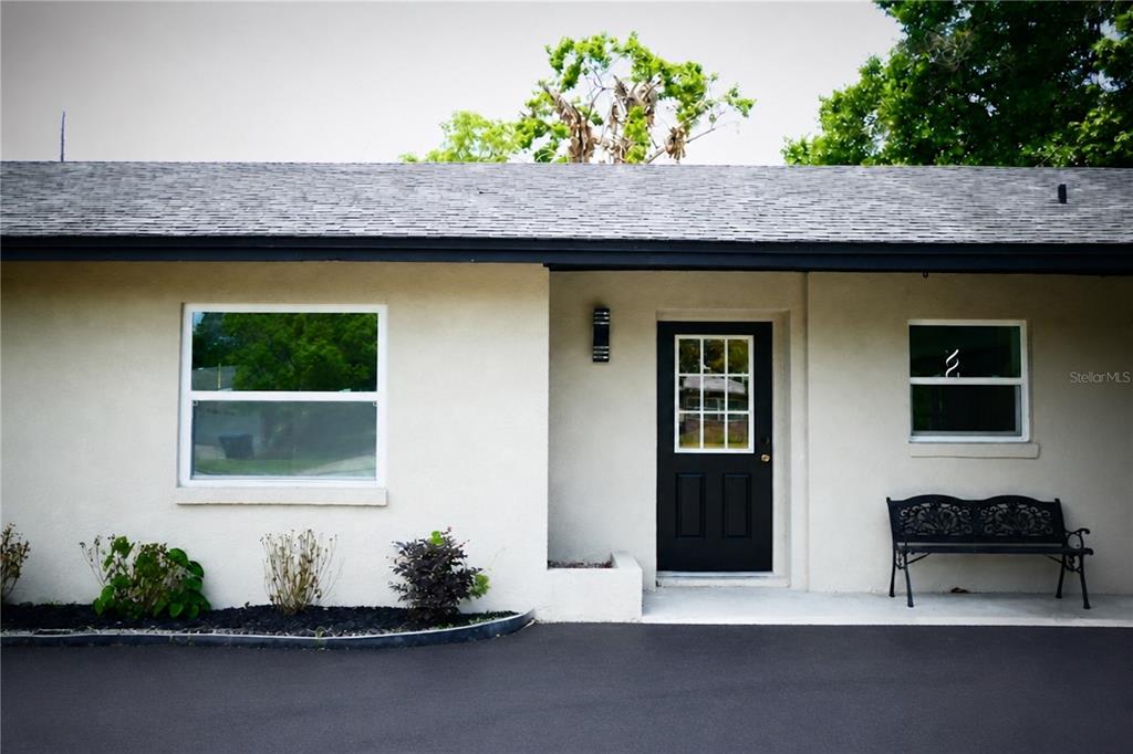 A single-story house exterior features a black front door, two windows, and a metal bench — 3202 TRADEWINDS TRAIL, ORLANDO, FL