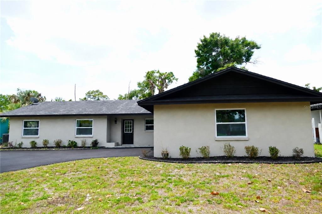 A single-story house with a beige stucco exterior, dark roof, and a black front door — 3202 TRADEWINDS TRAIL, ORLANDO, FL