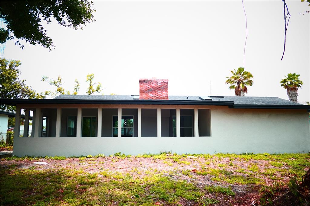 The exterior of a single-story house features a brick chimney and a long screened-in porch — 3202 TRADEWINDS TRAIL, ORLANDO, FL