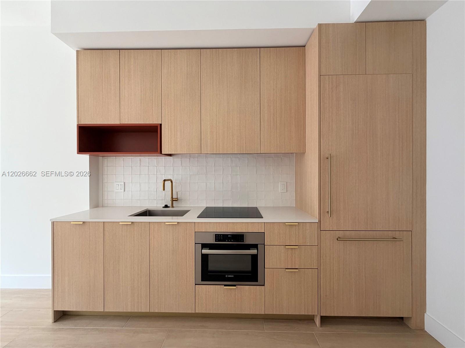 A modern kitchen features light wood cabinetry, a white tile backsplash, and a red open shelf — 90 NE 32nd St. # 209, Miami FL 33137, MIAMI, FL