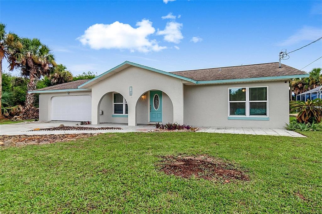 A single-story house with a light-colored exterior, arched entryway, turquoise front door, and attached garage — 2448 S DAYTONA AVENUE, FLAGLER BEACH, FL