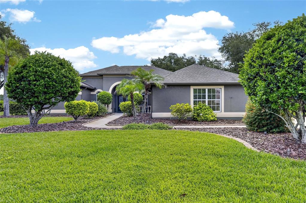 A single-story gray house with a front walkway, palm trees, and manicured landscaping — 7508 DUNBRIDGE DRIVE, ODESSA, FL