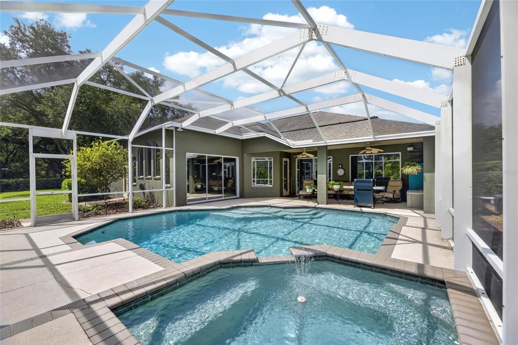 A screened-in patio features a swimming pool, a raised spa, and a covered seating area — 7508 DUNBRIDGE DRIVE, ODESSA, FL