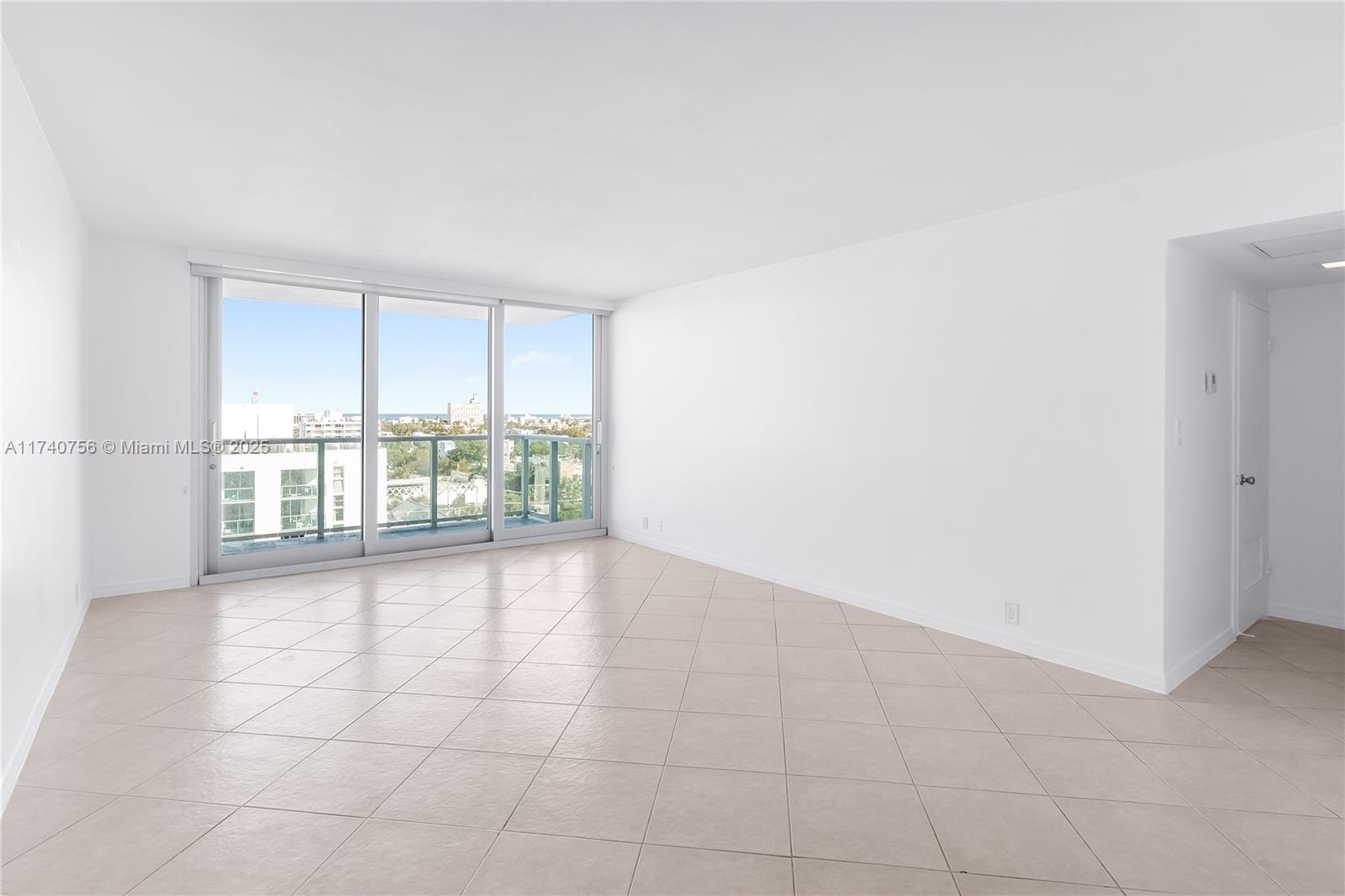 An empty room with white walls, light-colored tile flooring, and a large sliding glass door — 1000 West Ave # 1008, Miami Beach FL 33139, MIAMI BEACH, FL