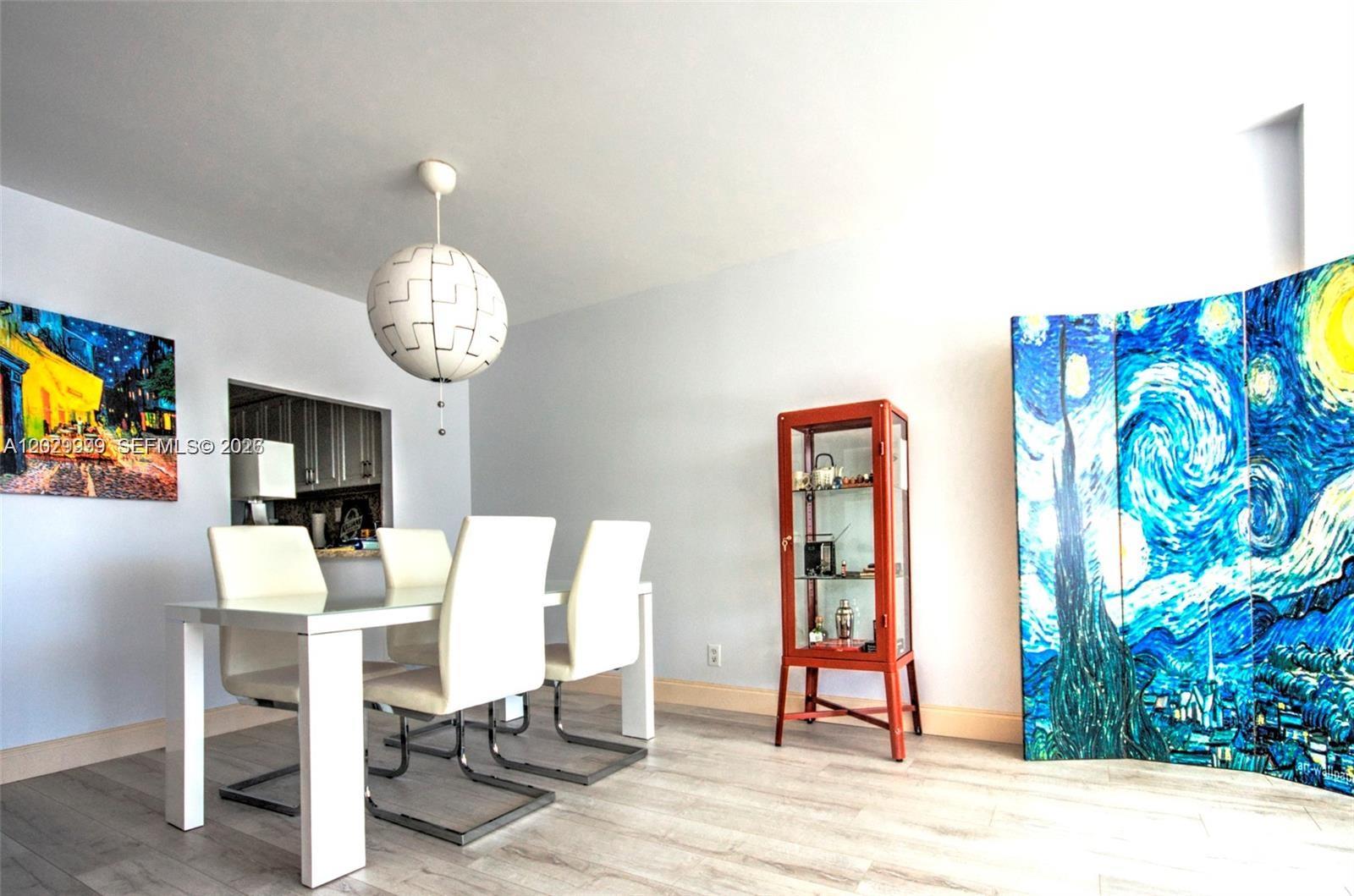 A dining room features a white table, four chairs, a glass display cabinet, and artwork — 1000 Parkview Dr # 426, Hallandale Beach FL 33009, HALLANDALE BEACH, FL