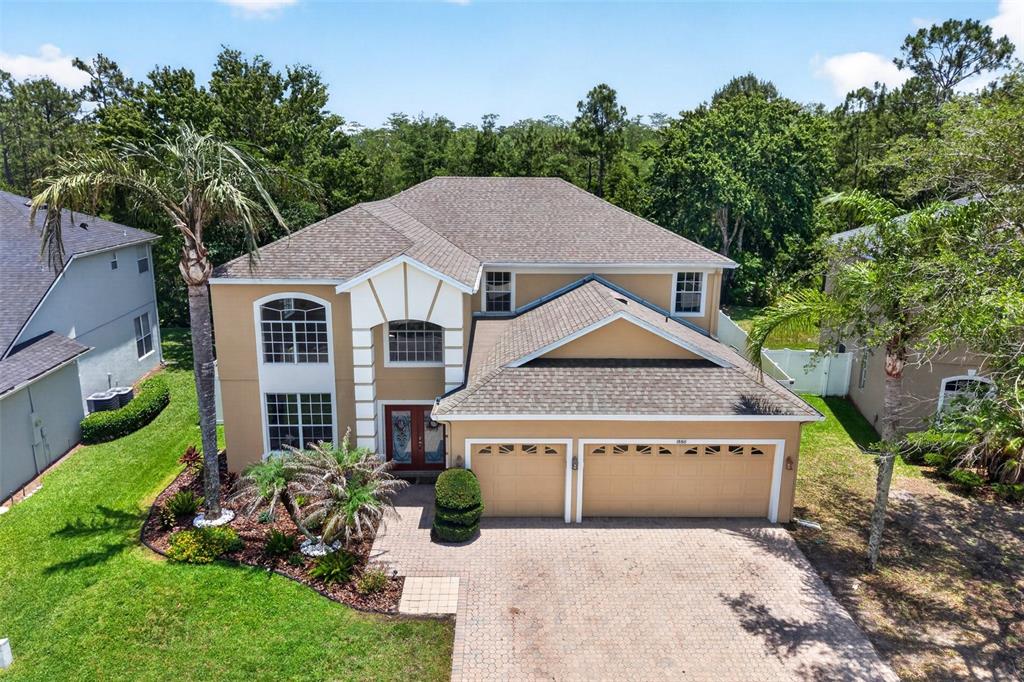 An aerial view of a two-story tan house with a two-car garage and palm trees — 1880 OAK GROVE CHASE DRIVE, ORLANDO, FL