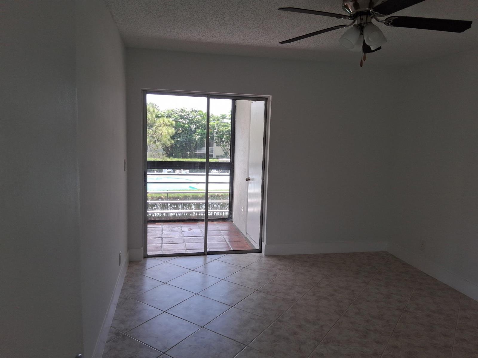 An empty room with light-colored tile flooring, a ceiling fan, and a sliding glass door — 2100 Springdale Boulevard # 303, Palm Springs FL 33461, PALM SPRINGS, FL