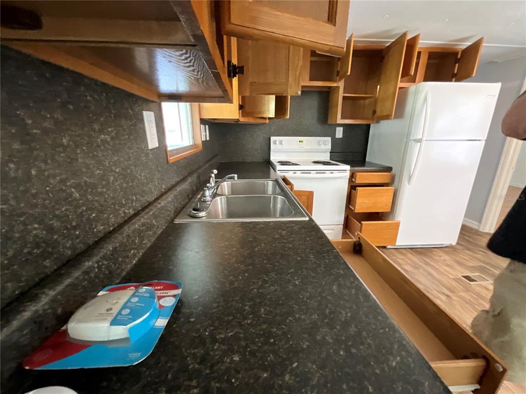 A kitchen features dark countertops, wood cabinets, a double sink, and a white refrigerator — 9624 SE 163RD LANE, SUMMERFIELD, FL