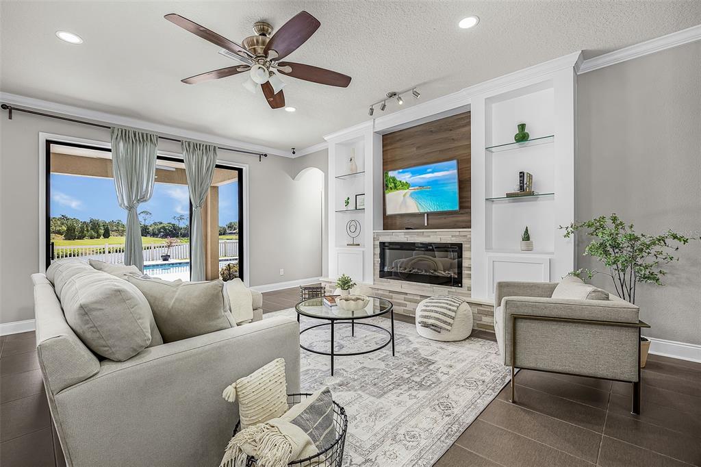 A living room features a fireplace, built-in shelving, a ceiling fan, and sliding glass doors — 835 129TH STREET NE, BRADENTON, FL