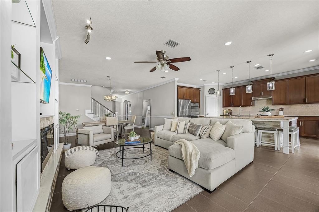 An open-concept living room and kitchen featuring a sectional sofa, dining area, and cabinetry — 835 129TH STREET NE, BRADENTON, FL