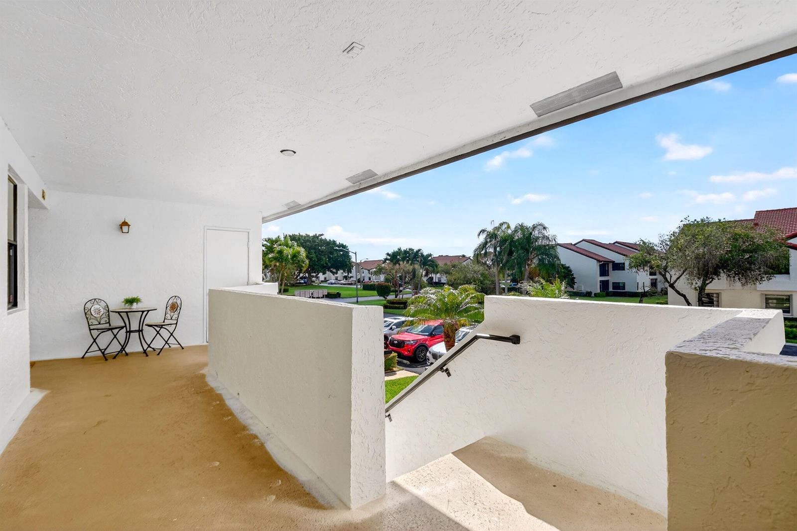A balcony features a small bistro set, a staircase with a handrail, and an outdoor view — 5903 Parkwalk Drive # 623, Boynton Beach FL 33472, BOYNTON BEACH, FL