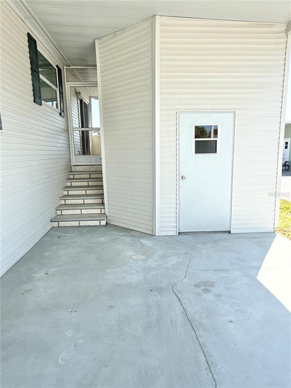 A concrete patio leads to a set of stairs and a white utility door — 6817 MOUNT PLEASANT ROAD NE UNIT 49, ST PETERSBURG, FL