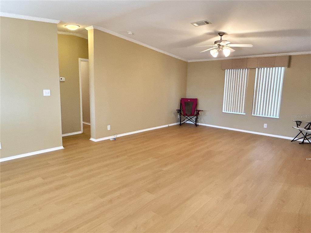 A spacious living room features light wood-look flooring, beige walls, and a ceiling fan — 6817 MOUNT PLEASANT ROAD NE UNIT 49, ST PETERSBURG, FL