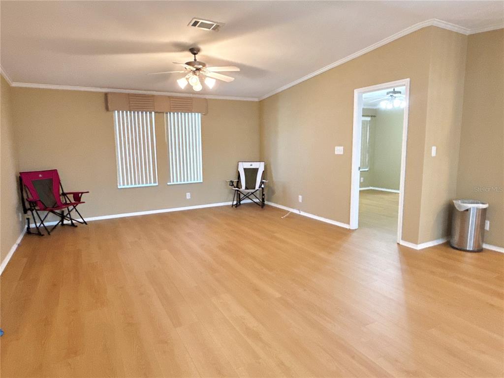 A living room with light wood-look flooring, beige walls, a ceiling fan, and two chairs — 6817 MOUNT PLEASANT ROAD NE UNIT 49, ST PETERSBURG, FL