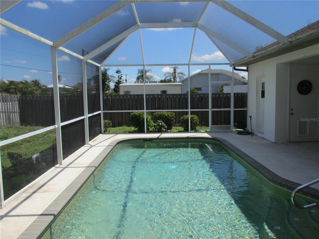A rectangular swimming pool is enclosed by a white-framed screen cage in a backyard — 23404 PEACHLAND BOULEVARD, PORT CHARLOTTE, FL