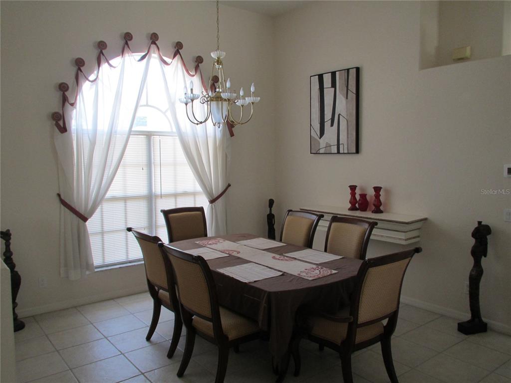 A dining room features a table with six chairs, a chandelier, and a large arched window — 23404 PEACHLAND BOULEVARD, PORT CHARLOTTE, FL