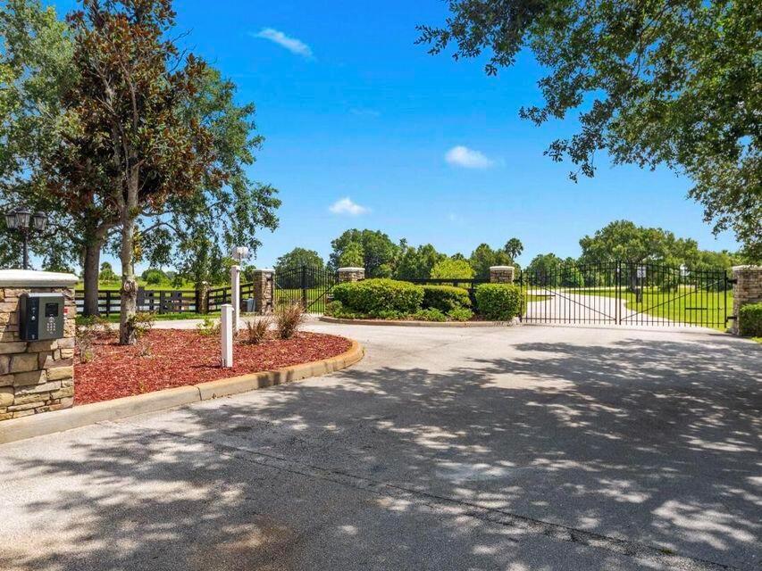 A paved driveway leads to a gated entrance with stone pillars and lush landscaping — 6635 SE 26th Trail, Okeechobee FL 34974, OKEECHOBEE, FL