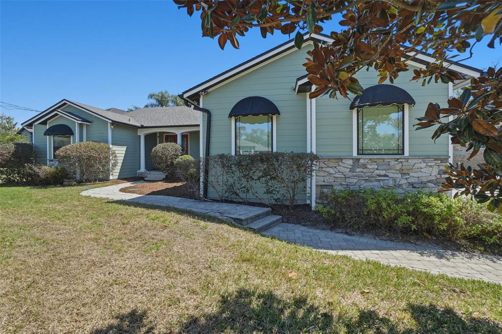 A light green single-story house features a red front door and black window awnings — 834 MILLSHORE DRIVE, CHULUOTA, FL