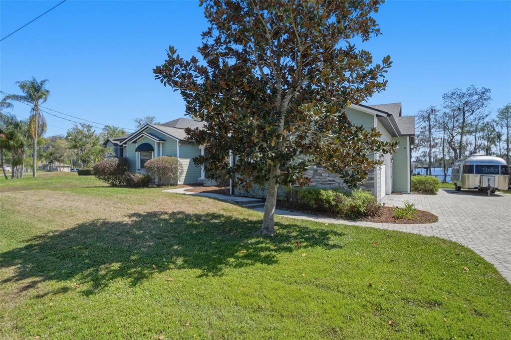 A light green house with a stone facade, white garage door, and paved driveway — 834 MILLSHORE DRIVE, CHULUOTA, FL