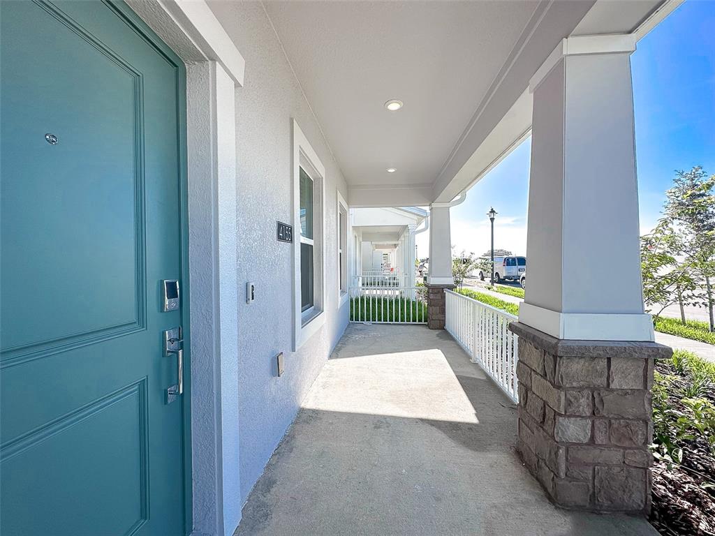 A covered front porch features a teal door, stone-based columns, and a white metal railing — 4155 CONJUNCTION WAY, APOPKA, FL